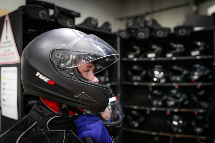 Driver putting on helmet and race suit.